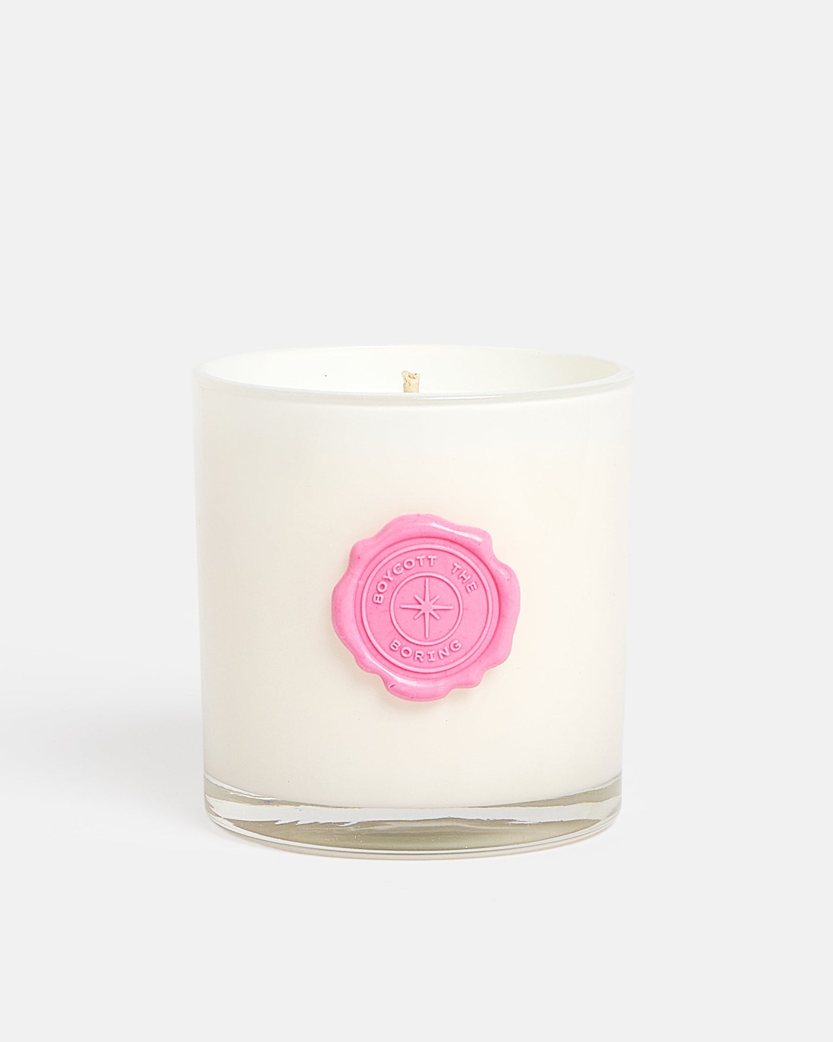 A white Tart By Taylor wax candle in a clear glass jar with a pink wax seal on the front, set against a solid light gray background.