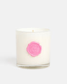 A white Tart By Taylor wax candle in a clear glass jar with a pink wax seal on the front, set against a solid light gray background.